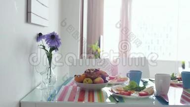 早上的早餐桌上有花束，在公寓厨房里有水果盘。 慢动作。 3840x2160